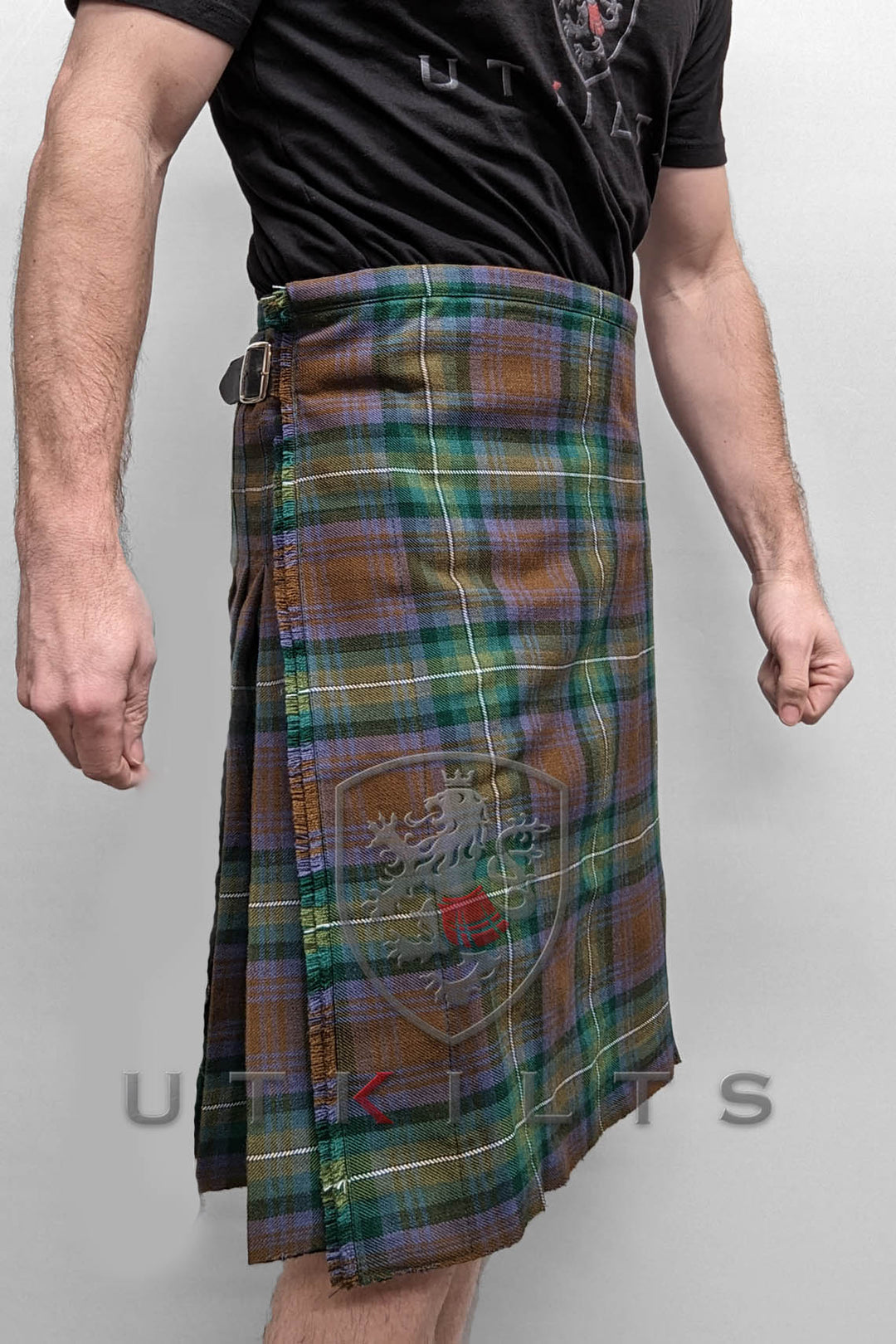 A man dressed in a kilt, complemented by a stylish belt, stands confidently, showcasing traditional Scottish attire.