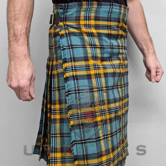 A man dressed in a yellow and blue tartan kilt stands confidently, showcasing the vibrant pattern and traditional style.