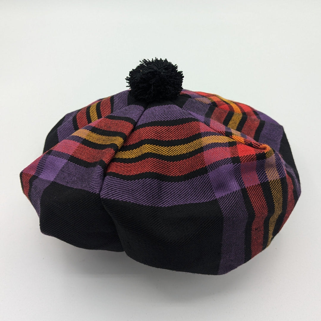 A fashionable black and purple plaid hat adorned with a cheerful pom pom, ideal for a trendy winter look.