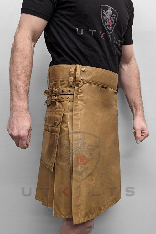 A man models a standard dark khaki utility kilt featuring two practical pockets, showcasing a blend of style and functionality.