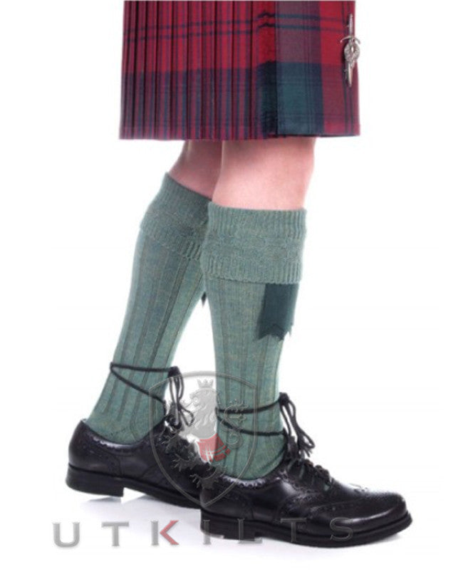 A man in a kilt paired with Premium Lovat Green Kilt Hose and black shoes.