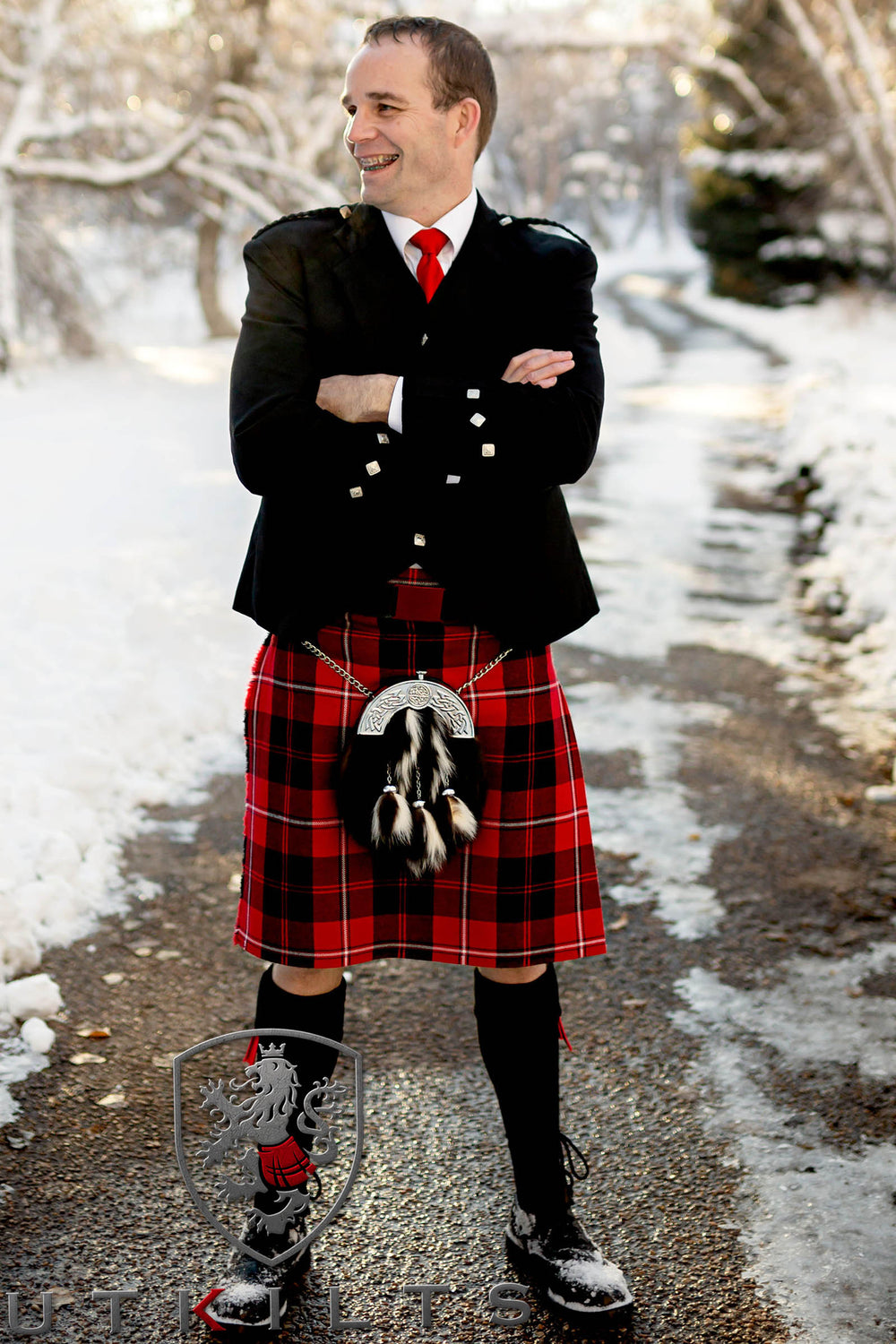 A man stands confidently in a 5-yard traditional tartan kilt, highlighting the elegance of Scottish attire.