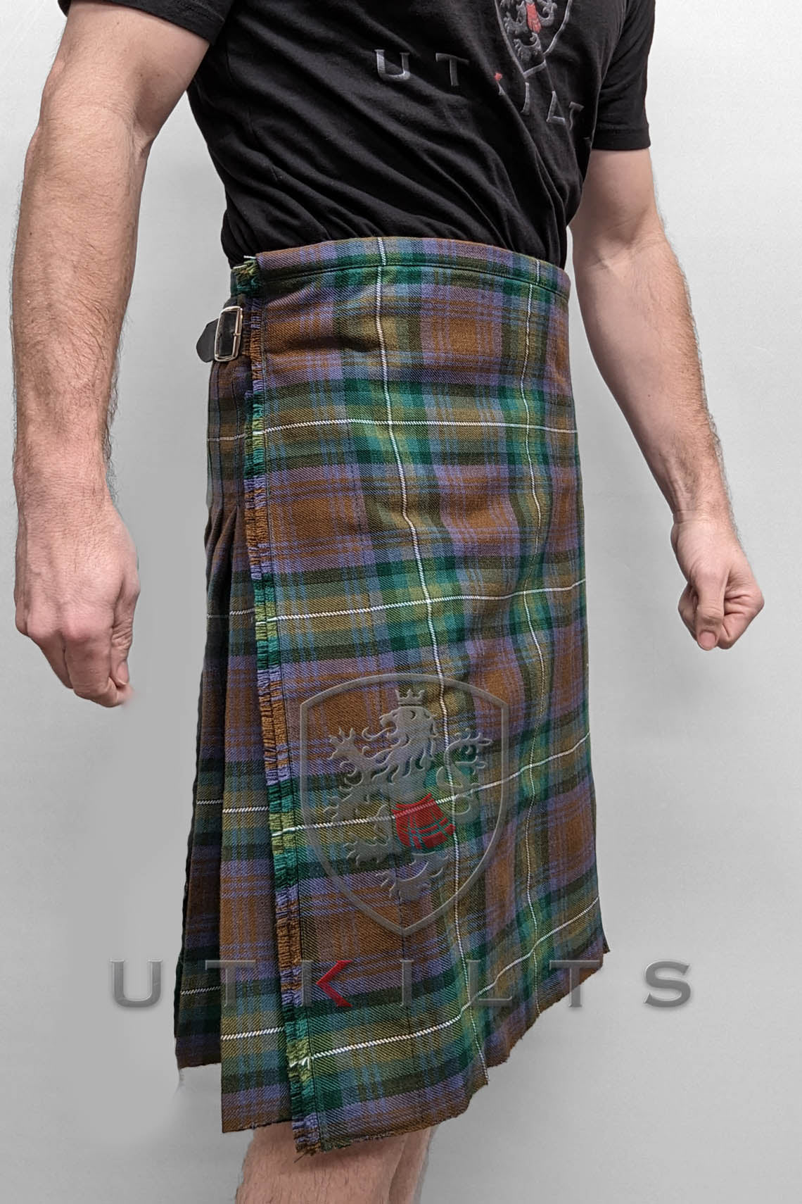  A man dressed in a kilt, complemented by a stylish belt, stands confidently, showcasing traditional Scottish attire.