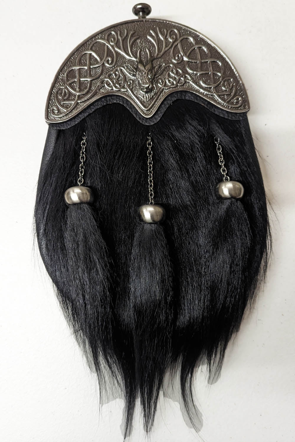 A formal black sporran made of goat hair, featuring fur and metal accents, showcasing a stag cantle design.