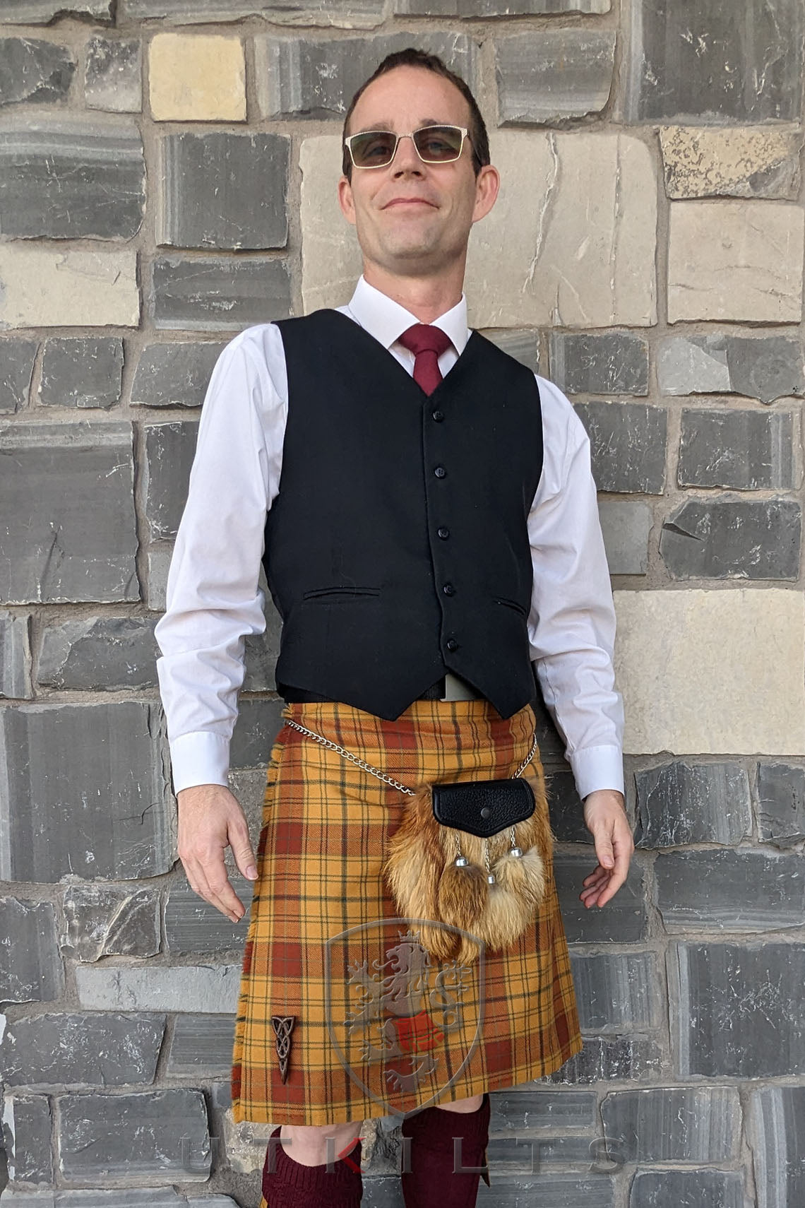 A man in a kilt stands beside a stone wall, showcasing the Special Order Made in Scotland 1783 Tartans, starting at $225.