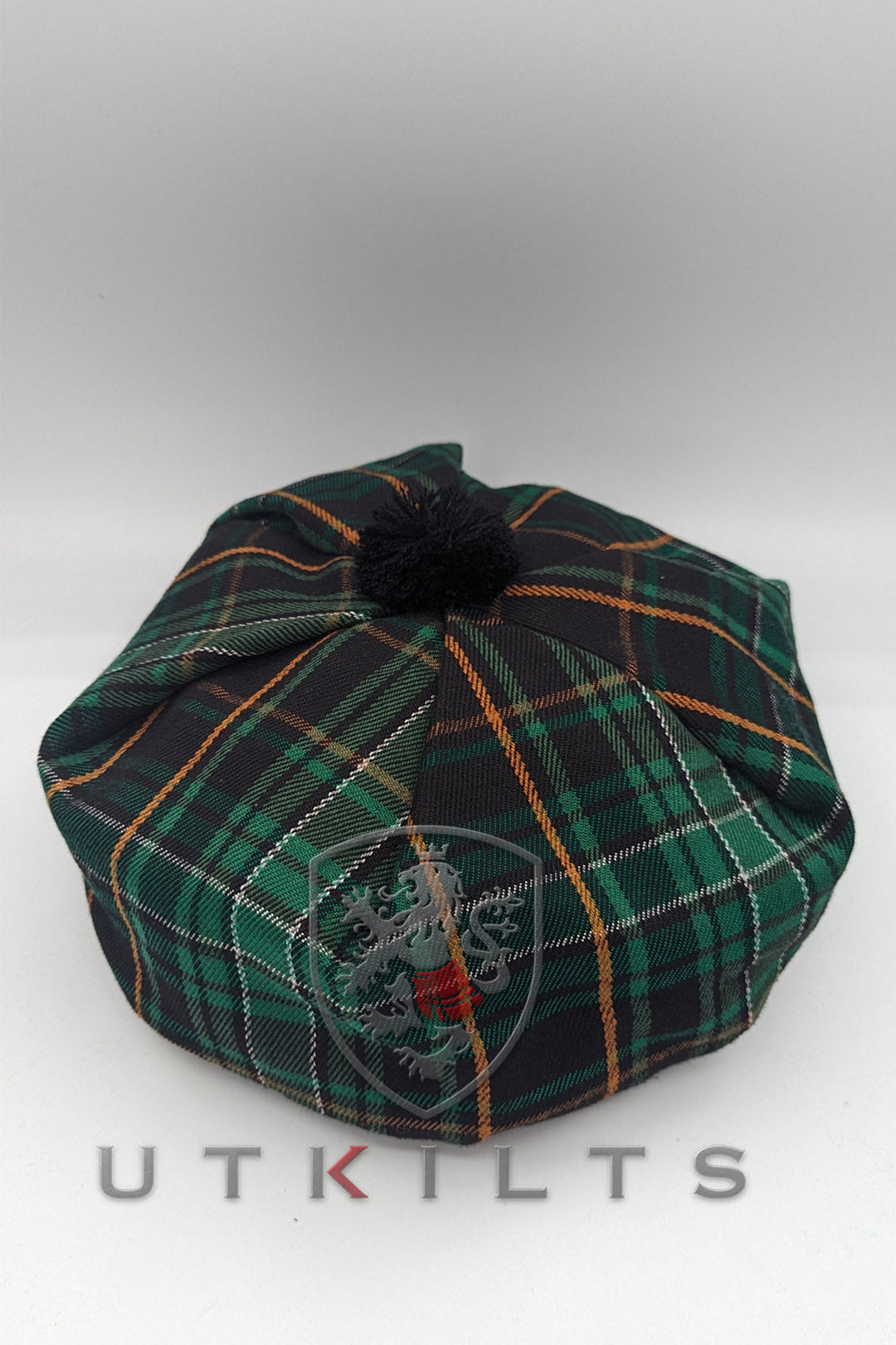 A green and black tartan hat featuring a pom pom, known as the Irish Black PV Tam, showcasing traditional design elements.