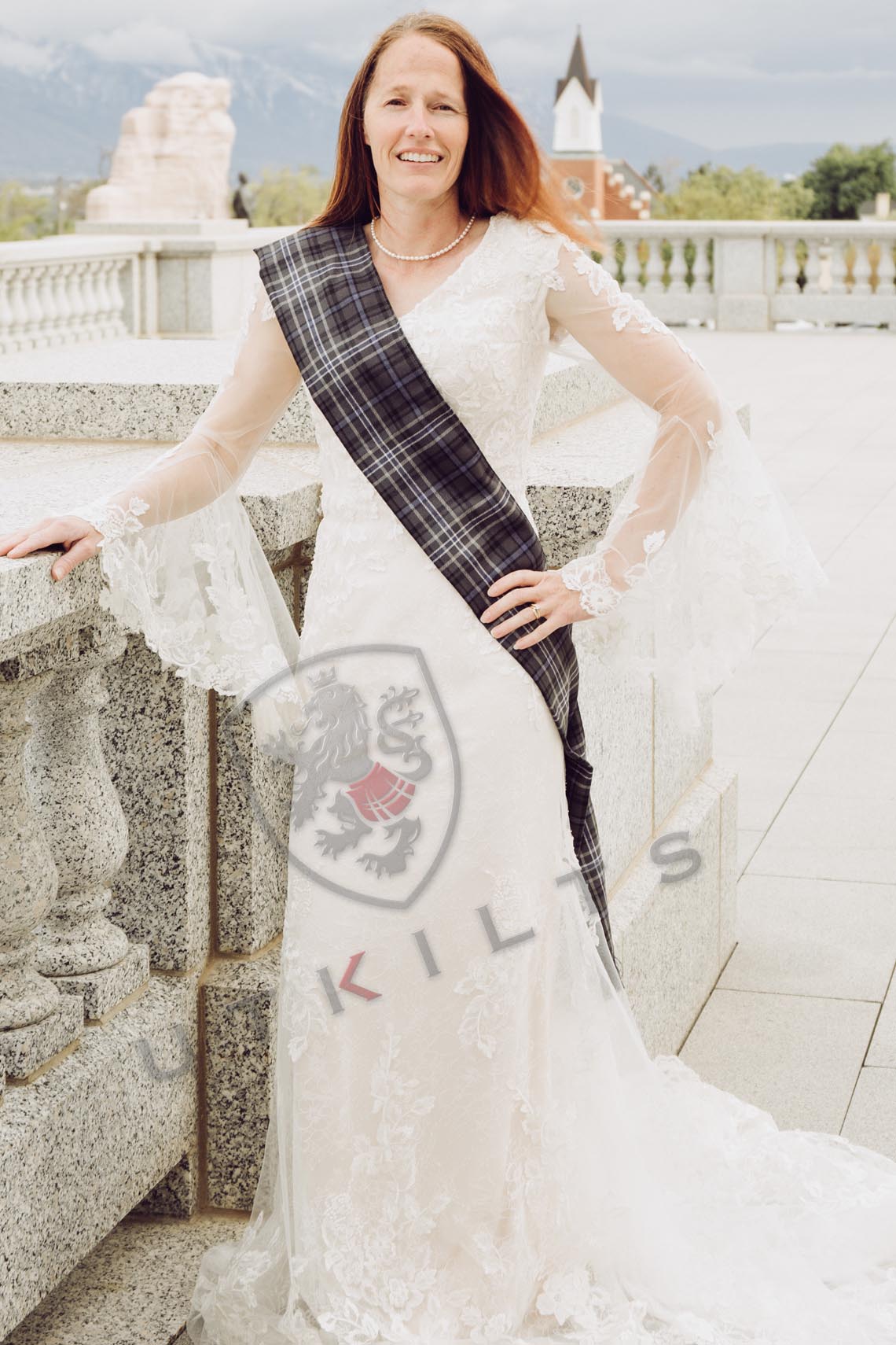 A woman in a wedding dress stands gracefully for a photo, featuring a premium wool ladies tartan sash from in-stock tartans.