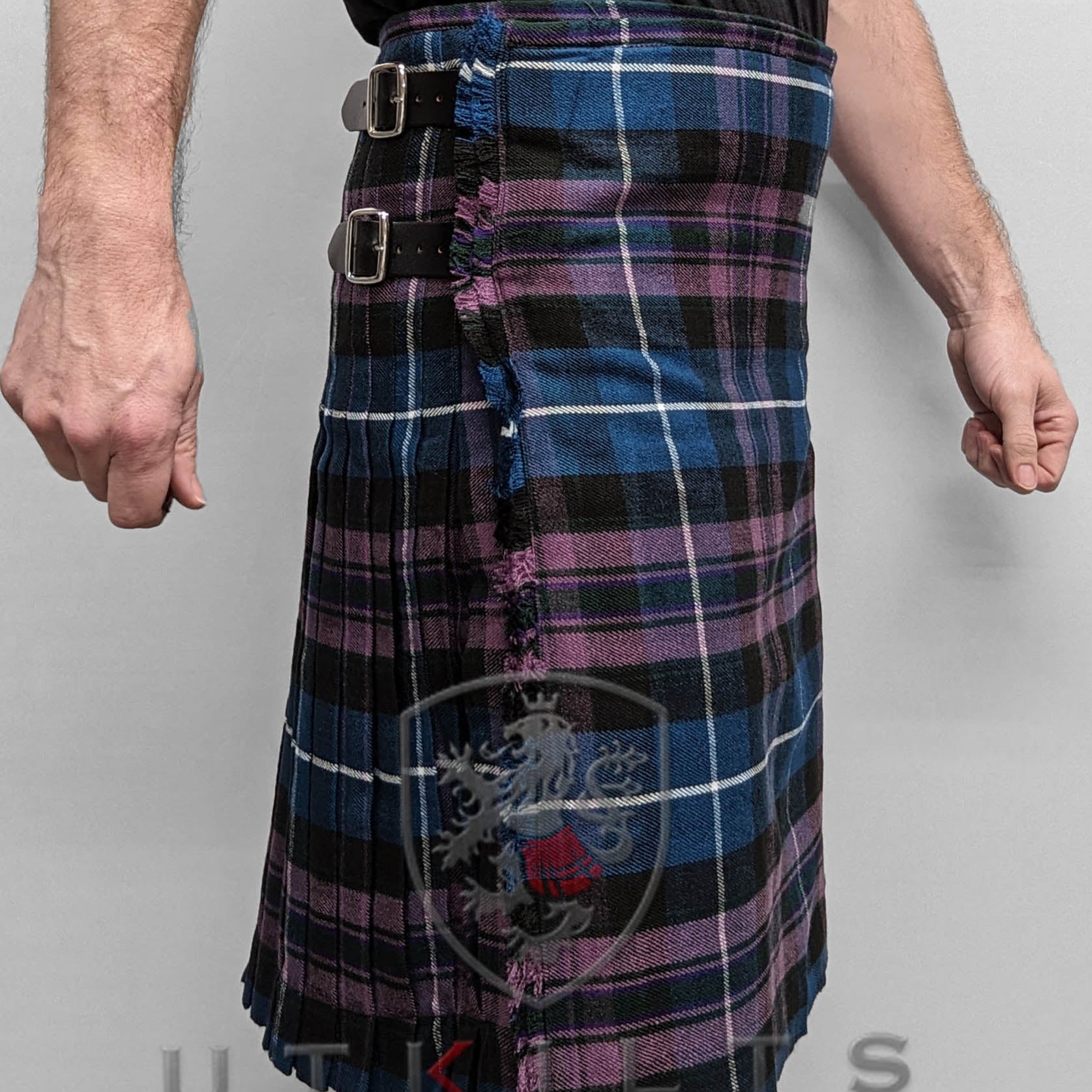 A man proudly wears a blue and purple plaid kilt, showcasing the traditional Pride of Scotland Tartan design.