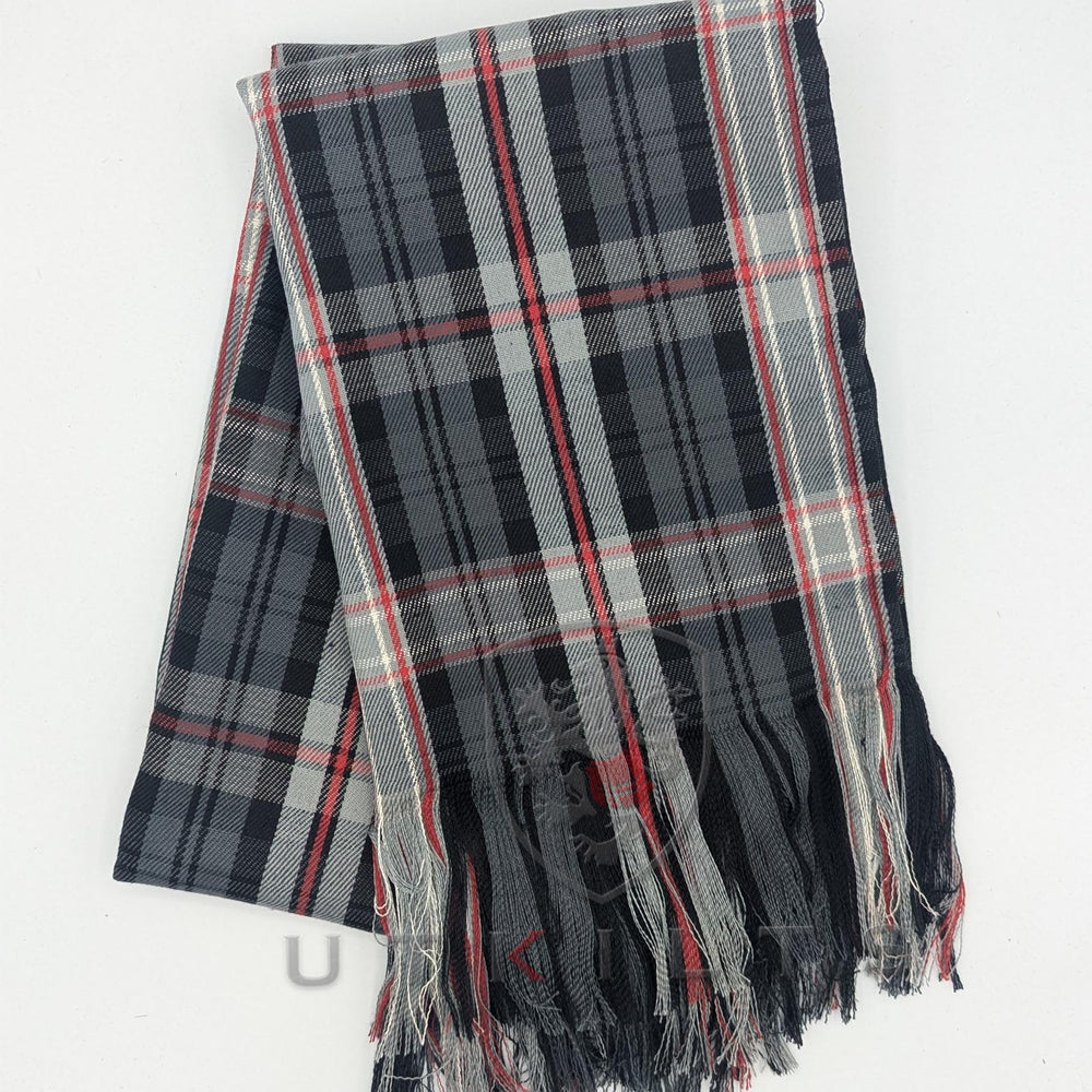 A black and red plaid scarf featuring fringes, elegantly draped and showcasing its vibrant pattern.
