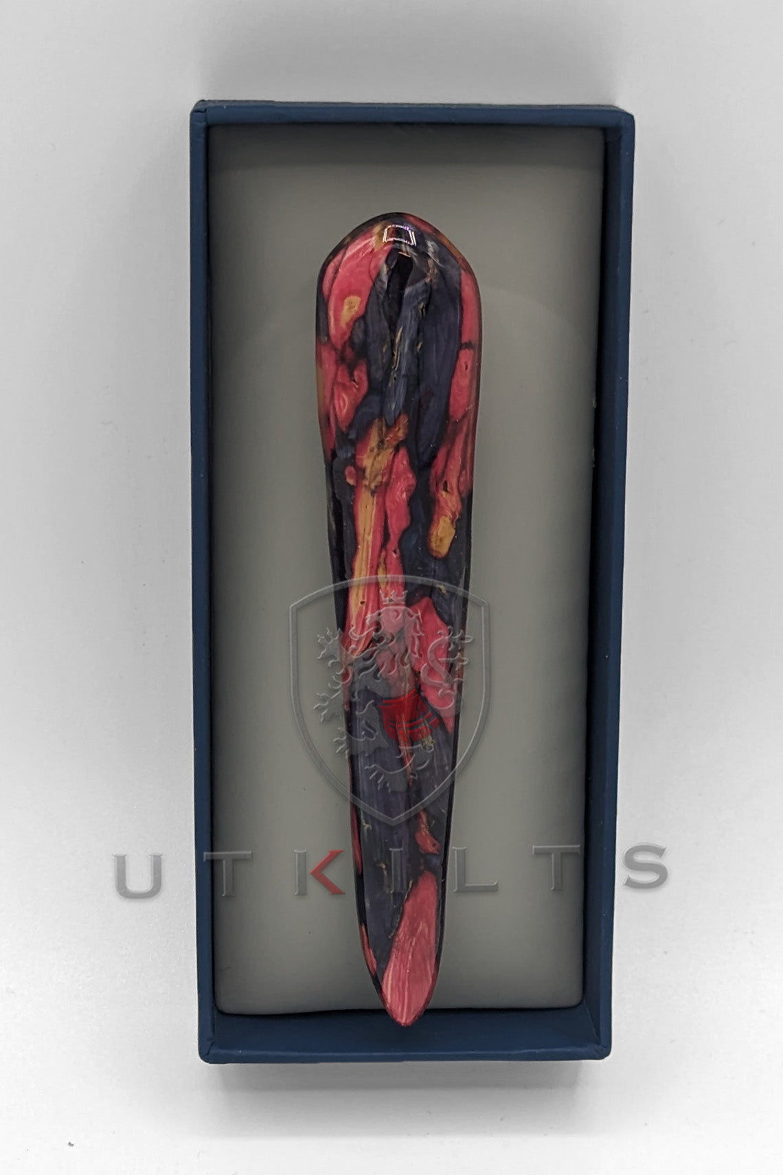 A pink and black marble-shaped object displayed inside a box, showcasing its unique colors and design.