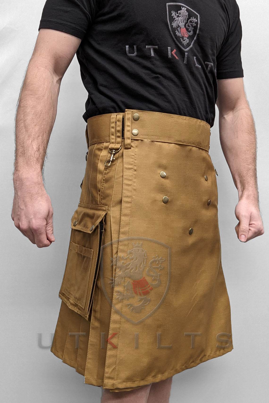 Front view of a man wearing a tan utility kilt with two pockets, part of the WILD Outdoor Wilderness Dark Khaki collection.