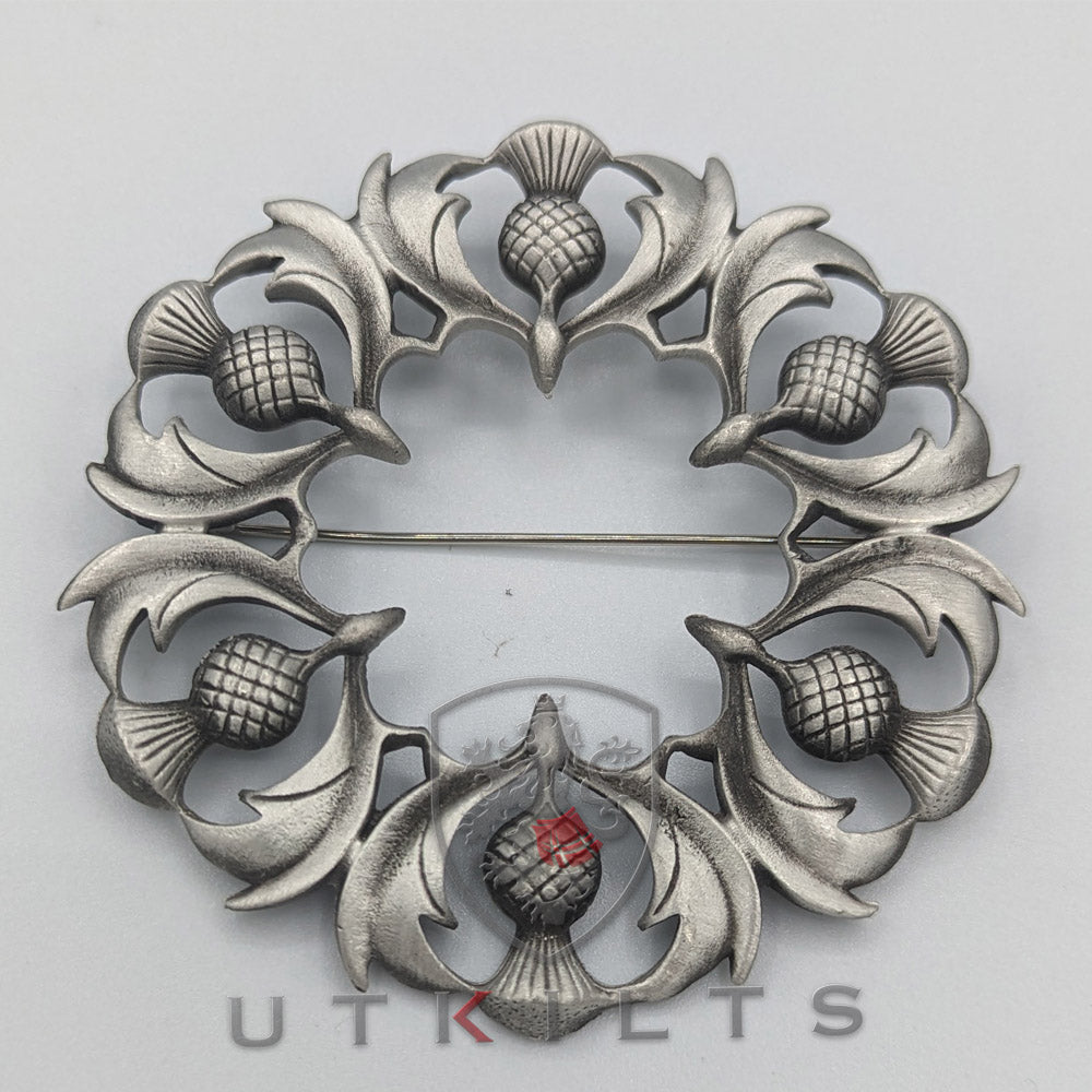 A silver thistle pin featuring an intricate flower design, showcasing elegance and craftsmanship in a compact form.