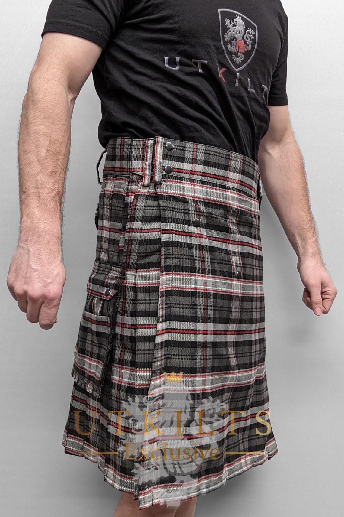 A man in a kilt featuring red and white tartan, paired with a black shirt, representing UTK Exclusives.