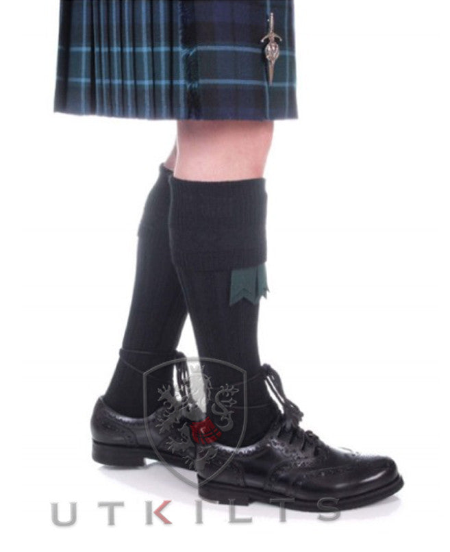 A man wearing a kilt and black shoes, featuring premium black kilt hose, exemplifying traditional Scottish style.